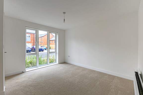 A room with a carpeted floor and a sliding glass door.