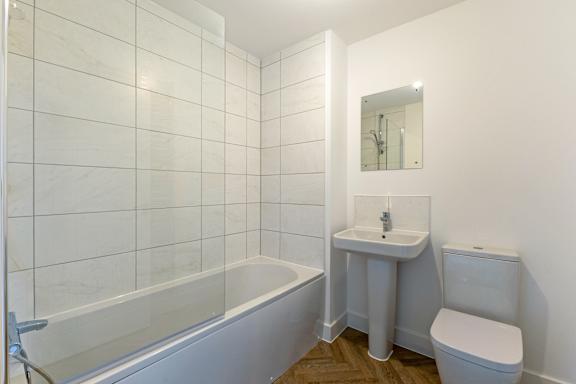 A white bathroom with a tub, sink, and toilet.