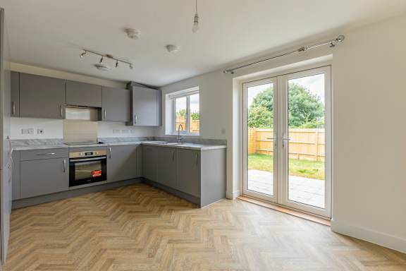 A kitchen with a wooden floor and a large window.