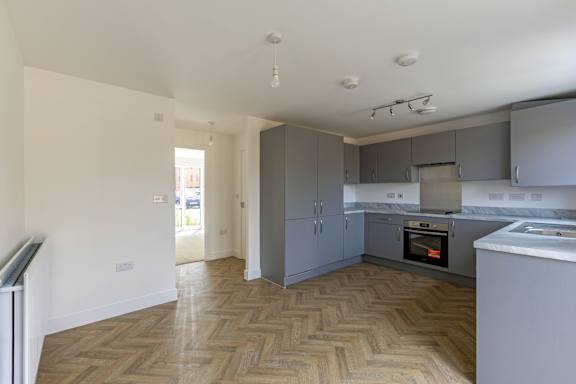A kitchen with wooden flooring and a grey cabinetry.