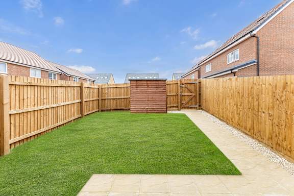 A backyard with a wooden fence and a green lawn.