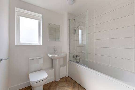 A white bathroom with a toilet, sink, and bathtub.