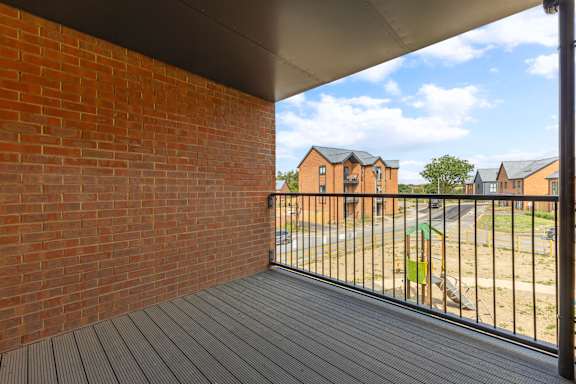 A balcony with a black railing and a wooden floor.