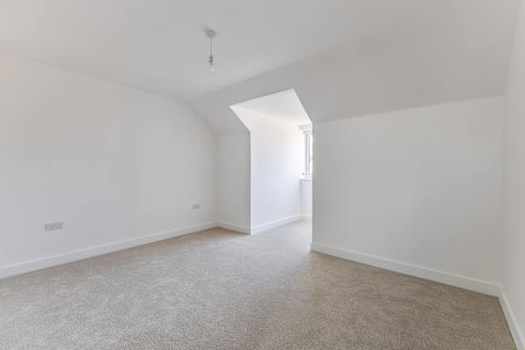 A white room with a carpeted floor and a small window.