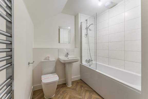 A white bathroom with a toilet, sink, and bathtub.