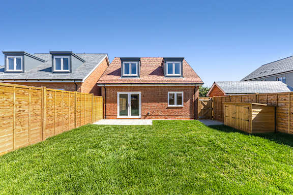 A house with a red brick facade and a wooden fence.