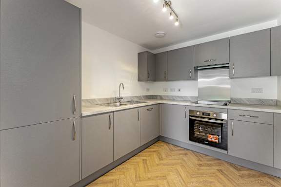 A kitchen with grey cabinets and a wooden floor.