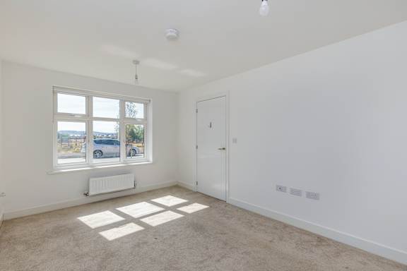 A room with white walls and a window overlooking a street.