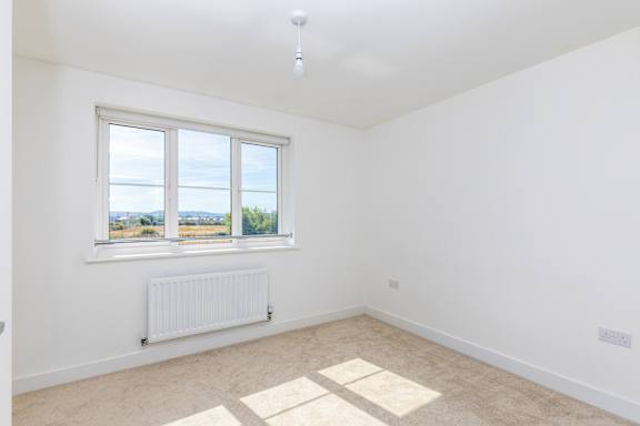 A white room with a window and a radiator on the wall.