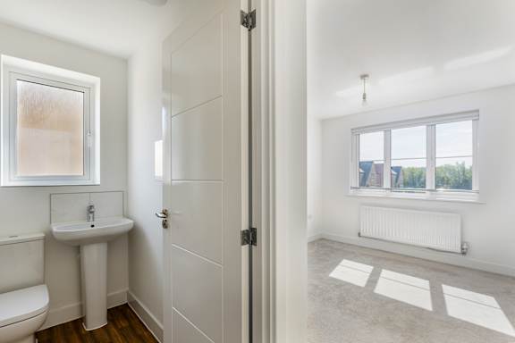 A bathroom with a toilet, sink, and a window.