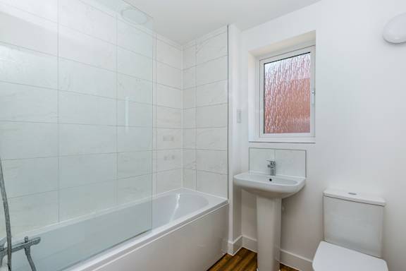 A white bathroom with a tub, sink, and toilet.