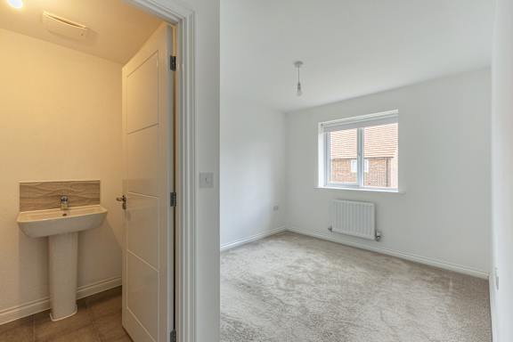 A white bathroom with a sink, toilet, and window.