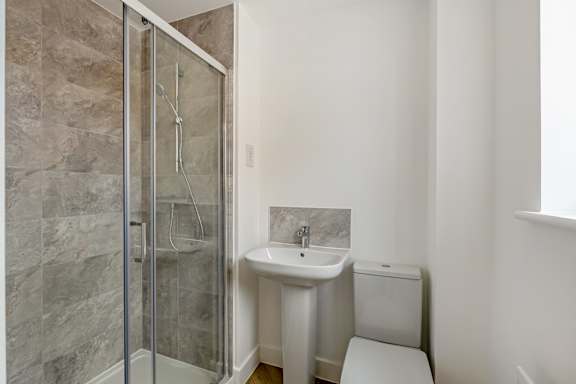 A bathroom with a walk-in shower, toilet, and sink.