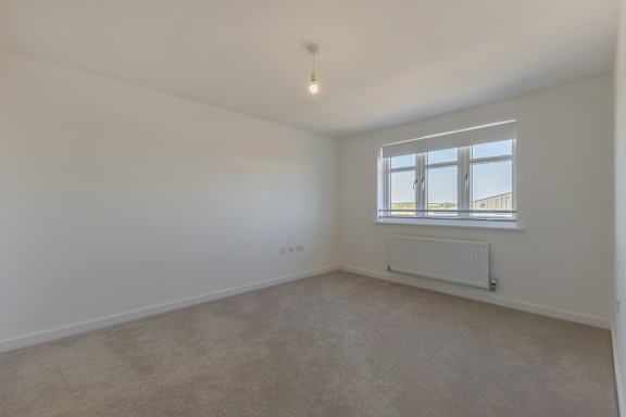 A room with a window and a radiator on the floor.