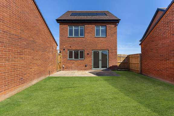 A red brick house with a green lawn in front.