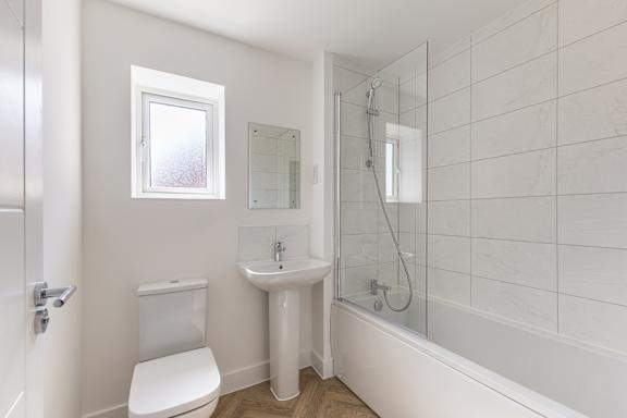 A white bathroom with a toilet, sink, and shower.