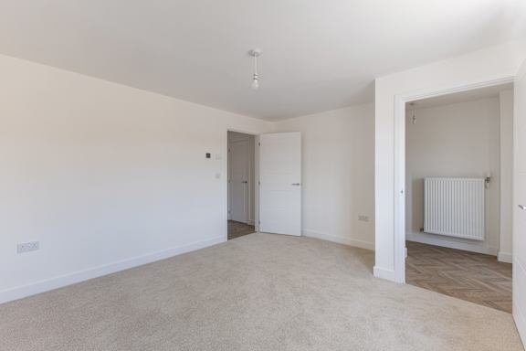 A spacious room with a carpeted floor and white walls.