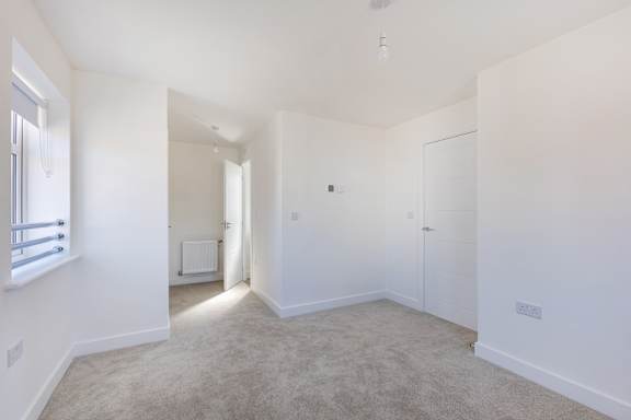 A spacious, empty room with white walls and carpeted floor.