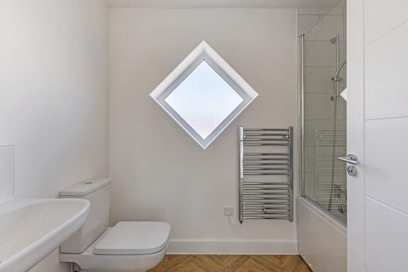 A white bathroom with a toilet, sink, and a window.