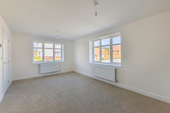 A room with two windows and a radiator on the wall.