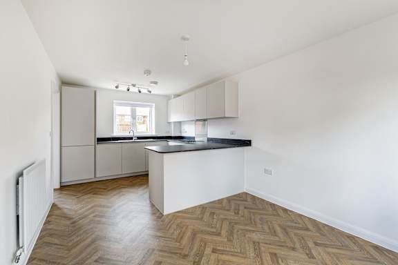 A kitchen with a wooden floor and white walls.