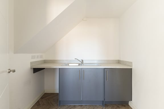 A kitchen with a white counter top and grey cabinets.