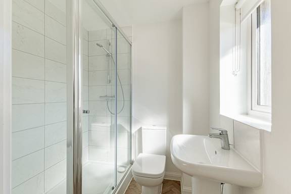 A white bathroom with a toilet, sink and shower.