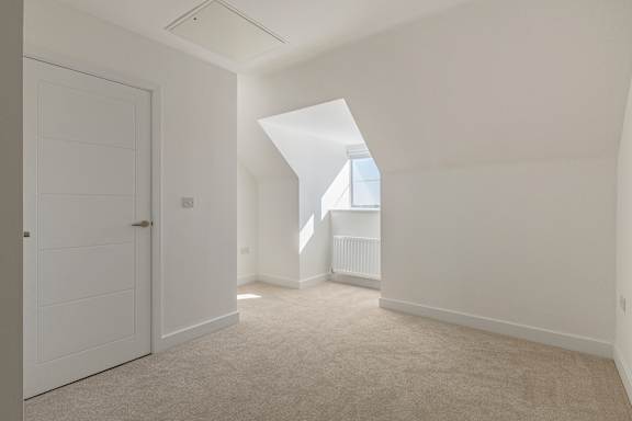 A white door is on the left side of a room with a window.