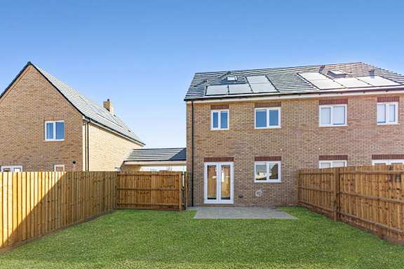 A house with a brown fence and a green lawn.