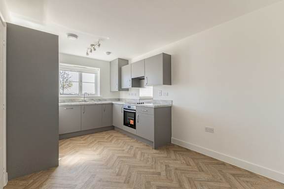 A modern kitchen with a wooden floor and white walls.
