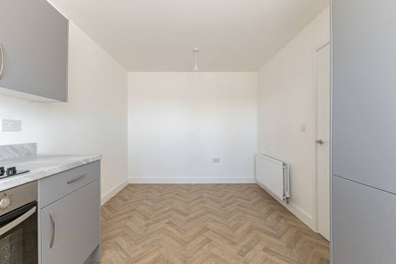 A kitchen with a wooden floor and white walls.