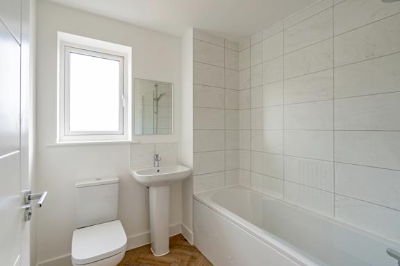 A white bathroom with a toilet, sink, and bathtub.