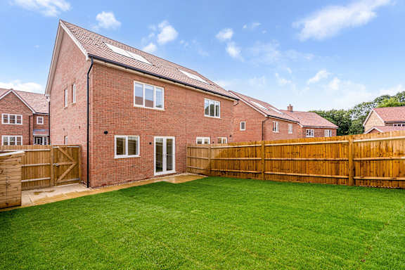 A red brick house with a wooden fence and a green lawn.