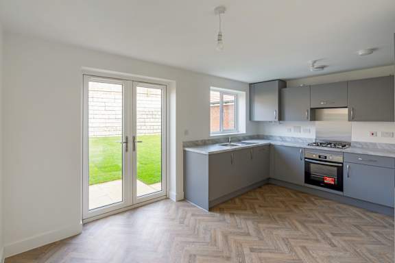 A kitchen with a wooden floor and a white wall.