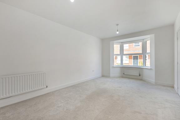 A large, empty room with a window and a radiator on the wall.