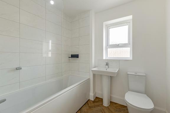 A white bathroom with a tub, toilet, and sink.