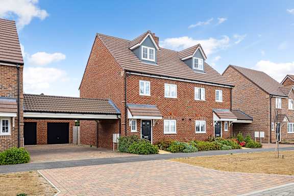 A large red brick house with a driveway in front.