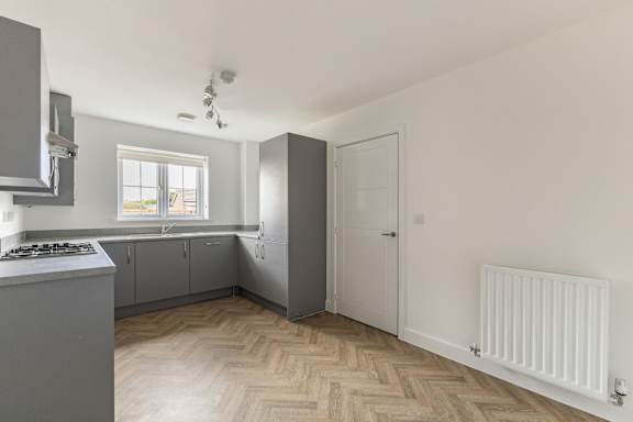 A kitchen with a white gas stove and wooden flooring.