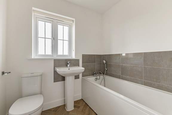 A white bathroom with a toilet, sink, and bathtub.