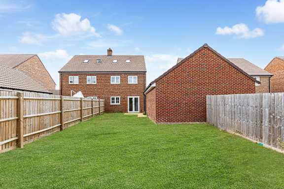 A backyard with a wooden fence and a green lawn.