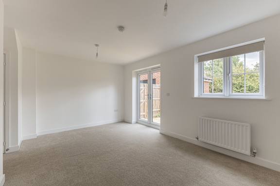 A spacious room with a carpeted floor and a window.