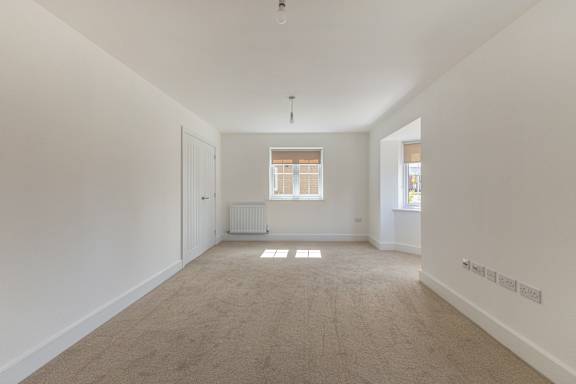 A spacious room with a window and a radiator on the wall.