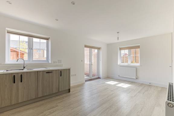 A spacious room with wooden floors and a window overlooking a building.