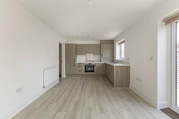 A spacious kitchen with wooden flooring and a large window.