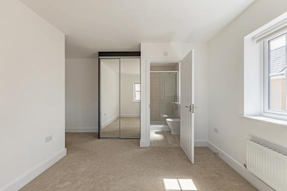 A white room with a carpeted floor and a large mirror on the wall.
