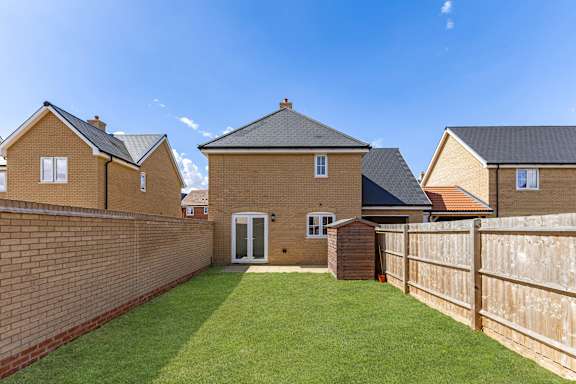A house with a brown brick wall and a green lawn.