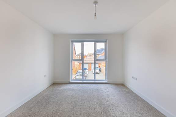 A room with a carpeted floor and a window showing an outdoor scene.