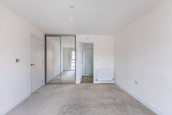 A room with a carpeted floor and a white wall.