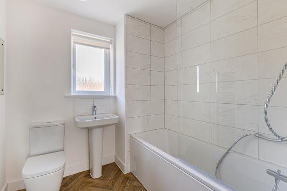 A white bathroom with a toilet, sink, and bathtub.