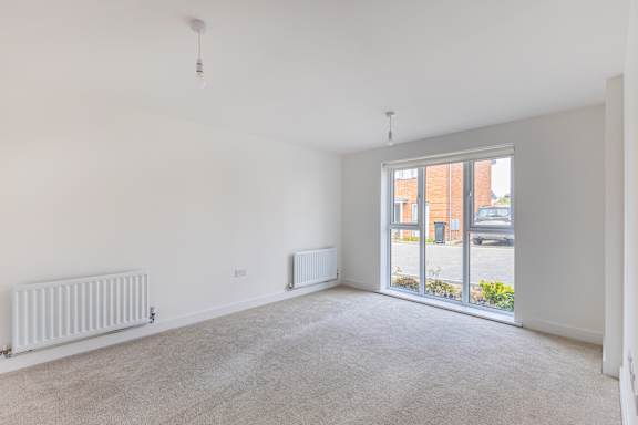 A room with a white wall and a window overlooking a street.